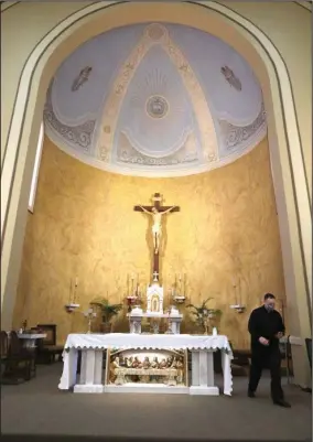  ?? The Sentinel-Record/Richard Rasmussen ?? AT THE ALTAR: The Rev. George Sanders walks near the altar of the Catholic Church of St. John the Baptist on Friday.