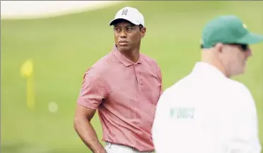  ?? Jamie Squire / Getty Images ?? Tiger Woods talks with caddie Joe Lacava on the range during a practice round prior to the Masters at Augusta National. Woods is the defending champ, but that win was 19 months ago.