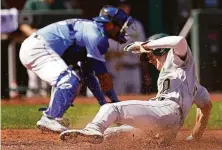  ?? Charlie Riedel / Associated Press ?? The A’s Mark Canha slides home to score on a single by Chad Pinder in the third inning of a win over the Royals.