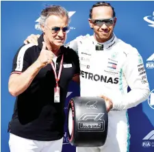  ?? — AFP photo ?? French former racing driver Jean Alesi (left) poses next to Hamilton after Hamilton received a pole position award after winning the pole position in the qualifying session at the Circuit Paul Ricard in Le Castellet, southern France at the Formula One Grand Prix de France.