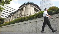  ?? (Yuriko Nakao/Reuters) ?? A MAN passes the Bank of Japan building in Tokyo.