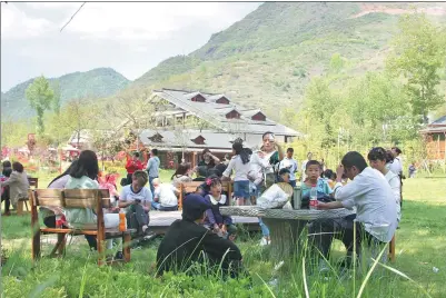  ?? PROVIDED TO CHINA DAILY ?? Tourists relax in a meadow in Huaqiao village in Kangxian county, Gansu province.