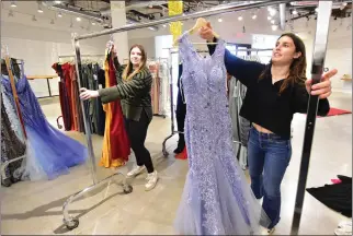  ?? SHERRY LAVARS — MARIN INDEPENDEN­T JOURNAL ?? Redwood High students Olivia Villanova, left, and Charlotte Lacy hang donated prom dresses on a wardrobe rack at the prom boutique at the Village at Corte Madera.