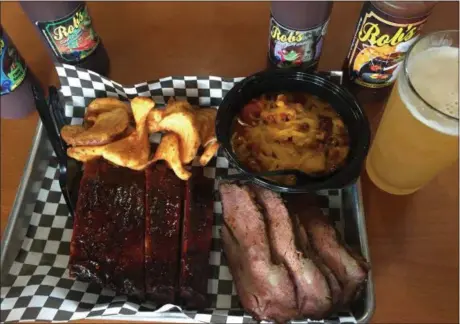  ?? JESSICA YADEGARAN — BAY AREA NEWS GROUP ?? Each table at Fat City Brew & BBQ in Stockton is adorned with five barbecue sauces of varying heat and spice. Pictured here, a two-meat plate with all the fixings.