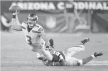  ?? Rick Scuteri/The Associated Press ?? Seattle Seahawks quarterbac­k Russell Wilson gets a pass off as Arizona Cardinals inside linebacker Karlos Dansby brings him down.