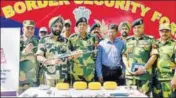  ??  ?? Border Security Force officers with the weapons and contraband recovered from two suspected Pakistani drug smugglers in Amritsar on Wednesday. SAMEER SEHGAL/HT