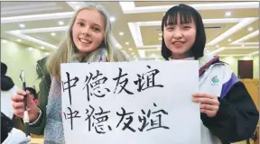  ?? WEI DONGSHENG / FOR CHINA DAILY ?? A German student and her Chinese peer show their calligraph­y work at a middle school in Ruichang, Jiangxi province on her visit to the city in March.