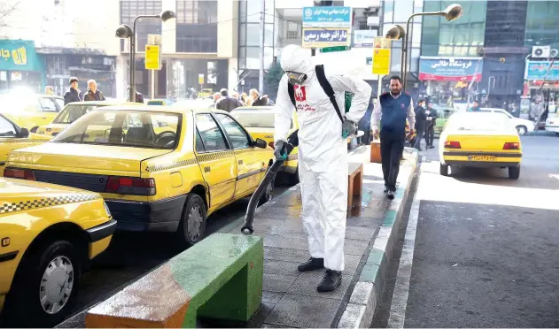  ?? Reuters ?? ↑
A health official wears a protective face mask as he sprays disinfecta­nt liquid to sanitise a taxi station in Tehran on Thursday.