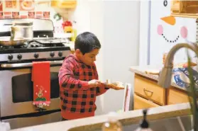  ??  ?? Ruben Magana de Cuevas, one of the family’s five children, makes a sandwich after dinner. The children contracted COVID19 when the parents did.