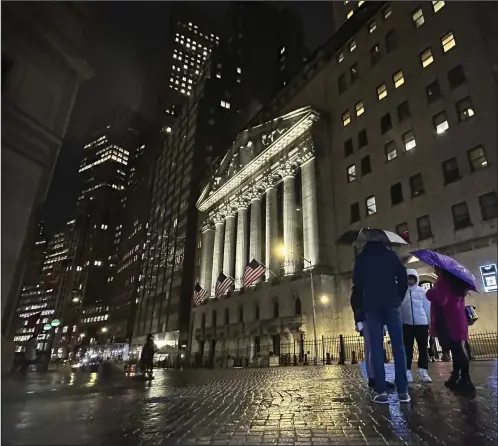  ?? (AP/Peter Morgan) ?? People huddle outside the New York Stock Exchange on Nov. 21 in New York.