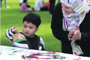  ?? Delores Johnson / The National ?? Liam Laguardia, 3, with Emirati artist Azza Al Qubaisi during the art workshop for children with autism at Umm Al Emarat Park in Abu Dhabi yesterday.