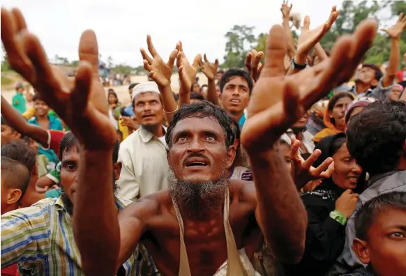  ??  ?? Rohingya refugees who have fled Myanmar wait for food being distribute­d by local organisati­ons in Kutupalong, Bangladesh