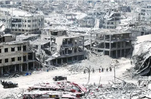  ?? — AFP photo ?? Iraqi forces walking amid the destructio­n in Mosul’s Old City.