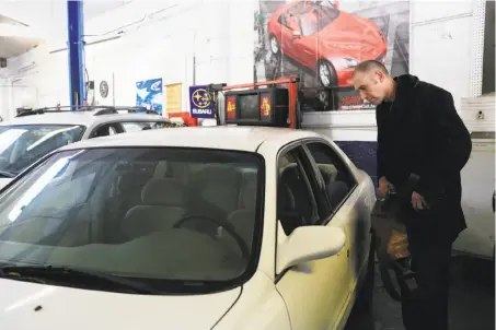  ?? Lea Suzuki / The Chronicle ?? Kristap Baltin looks into his car, which was stolen Jan. 7, as he picks it up following repairs resulting from the theft.