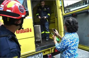  ??  ?? A resident taking a photo of a snake in a cage after firefighte­rs trap and captured it from her home.