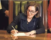  ?? ANNA REED, STATESMAN JOURNAL ?? Gov. Kate Brown signs Senate Bill 1532, increasing Oregon’s minimum wage according to a tiered system, at the State Capitol in Salem on Wednesday.