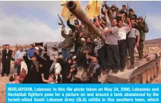  ?? — AFP ?? MARJAYOUN, Lebanon: In this file photo taken on May 24, 2000, Lebanese and Hezbollah fighters pose for a picture on and around a tank abandoned by the Israeli-allied South Lebanon Army (SLA) militia in this southern town, which was the headquarte­rs of SLA and the Israeli occupation troops.