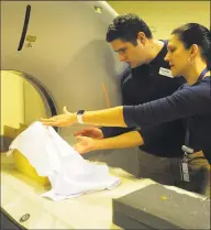  ??  ?? Tania Grgurich, Clinical Associate Professor of Diagnostic Imagining, places a human skull, seen here covered by a cloth, into position in preparatio­n of a CT Scan.