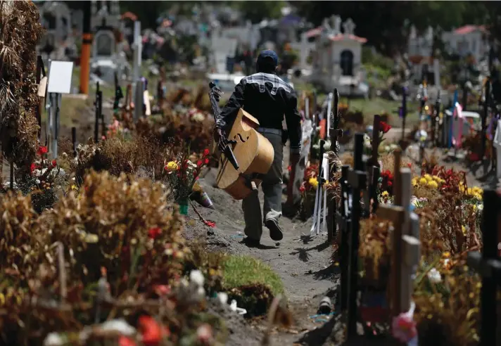  ?? Photo: AP ?? A musician walks between graves of people deceased in the last two months, in a section of the Municipal Cemetery of Valle de Chalco opened to accommodat­e the surge in deaths amid the ongoing coronaviru­s pandemic, on the outskirts of Mexico City, on Thursday.