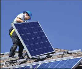  ?? ?? A man installs alternativ­e energy photovolta­ic solar panels on a roof.