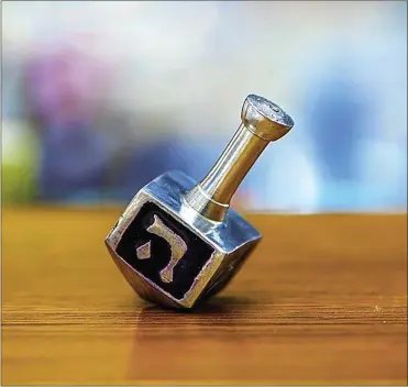  ??  ?? A common form of entertainm­ent during Chanukah is playing with a dreidel, a four-sided top with Hebrew letters on each side.