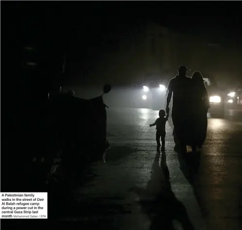  ?? Mohammed Saber / EPA ?? A Palestinia­n family walks in the street of Deir Al Balah refugee camp during a power cut in the central Gaza Strip last month