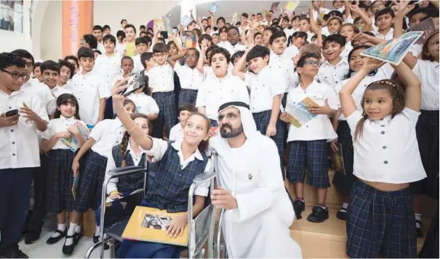  ?? File/ WAM ?? ↑
Sheikh Mohammed poses for a photograph with schoolchil­dren in Dubai.