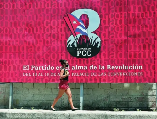  ?? EFE ?? Una mujer camina frente a una valla que promociona el congreso del Partido Comunista cubano