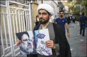 ?? VAHID SALEMI / ASSOCIATED PRESS ?? A clergyman who supports presidenti­al candidate Ebrahim Raisi displays posters of the law professor Wednesday in Tehran. Raisi poses the strongest challenge to Rouhani.