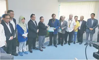  ?? ?? Board member of SK Methodist, Kapit, Laso Lanang, receives the Unifor grant from Abang Johari (right) as state cabinet ministers and others look on.