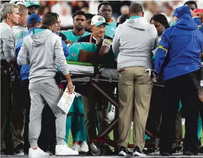  ?? GETTY IMAGES ?? Dolphins quarterbac­k Tua Tagovailoa is tended to after he suffered neck and head injuries while being sacked Thursday.