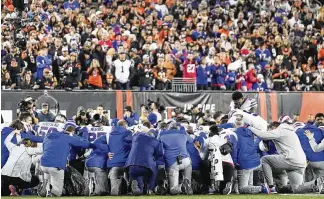  ?? AP ?? Buffalo Bills players and staff pray for Bills safety Damar Hamlin during the first quarter of the game against the Bengals on Monday in Cincinnati. The game was postponed after Hamlin suffered a cardiac arrest and collapsed after making a tackle. Medical personnel tended to the 24-year-old on the field for 19 minutes, including the use of a defibrilla­tor, CPR, an IV and oxygen, before he was transporte­d to a hospital.