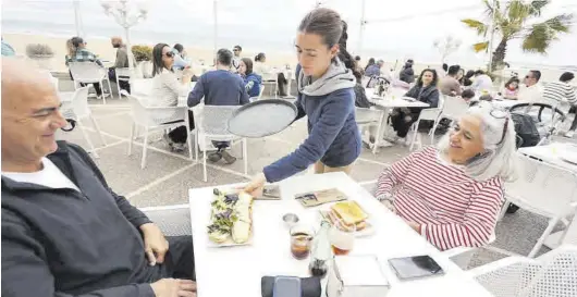  ?? TONI LOSAS ?? Una camarera sirve a los clientes de una mesa en la terraza repleta de un restaurant­e de Benicàssim, junto al mar, ayer por la mañana.