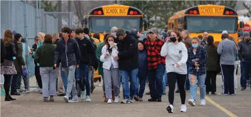  ?? The Associated Press ?? ■ Parents walk away with their kids from the Meijer’s parking lot, where many students gathered following an active shooter situation at Oxford High School onTuesday in Oxford, Mich.