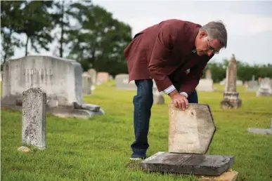  ?? Staff photo by Joshua Boucher ?? Dwight Byrd lifts part of a cracked gravestone to show the inscriptio­n at the Sand Hill Cemetery near Simms, Texas. Over time, gravestone­s can settle and crack.