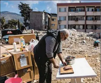  ?? ?? A man prepares meal outdoors near his destroyed house on Tuesday a day after 6.4-magnitude earthquake hit Hatay province in southern Turkey.