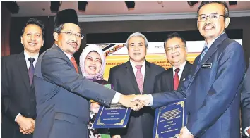  ??  ?? Misnu (front left) and Amiruddin exchange documents. From second right are Alexander, Awang Tengah, and Fatimah.