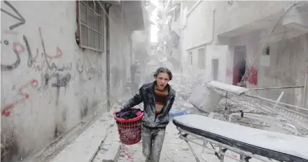  ?? — Reuters ?? A boy carries his belongings at a site hit by a barrel bomb in Aleppo’s Al Fardous district, Syria, in this file photo.