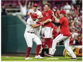  ?? AARON DOSTER / AP ?? Christian Encarnacio­n-Strand (bottom left) celebrates a walk-off with Spencer Steer (back), TJ Friedl (middle) and Andrew Abbott on Tuesday in Cincinnati.