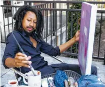  ?? STAFF PHOTO BY DOUG STRICKLAND ?? Artist Genesis the Greykid works on a painting outside the Frothy Monkey coffee shop in July, 2018.