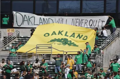  ?? PHOTOS BY NHAT V. MEYER — BAY AREA NEWS GROUP ?? Oakland Athletics fans hold up banners in the right field stands during the A's game against the Detroit Tigers in the seventh inning at the Coliseum in Oakland on Sept. 24, 2023.