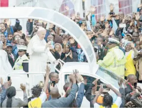  ??  ?? El papa Francisco saluda a la multitud desde su vehículo especial a su llegada a la Universida­d de Nairobi, donde dirigió su enfática alocución.