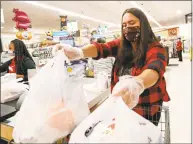  ?? Kathy Willens / Associated Press ?? Alexandra Lopez-Djurovic places bags of groceries in her cart after shopping for a client in an Acme supermarke­t in Bronxville, N.Y. on Wednesday.