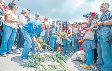  ??  ?? Venezolano­s colocan flores luego de una misa por Miguel Castillo, quien murió tras ser herido con un arma de fuego en las protestas del miércoles en Caracas.