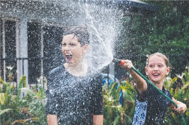  ?? Picture: BRENDAN RADKE ?? WELCOME SPRAY: Stella Sattler, 8, and her brother Scott, 10, cool off under the garden hose at Redlynch.