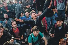  ?? Angelos Tzortzinis AFP/Getty Images ?? MIGRANTS block a road outside Lesbos’ port after rumors they could be taken to Greece’s mainland amid a surge in crossings after Turkey opened its borders.