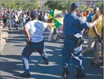  ?? PICTURE: REUTERS ?? DESPERATE BID: A police officer is at the ready as mourners force their way through a checkpoint on the way to the Union Buildings.