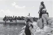  ?? Anne Chaon / AFP / Getty Images ?? Crew members of the Ocean Viking rescue ship rescue migrants from an inflatable boat Saturday in the Mediterran­ean Sea.