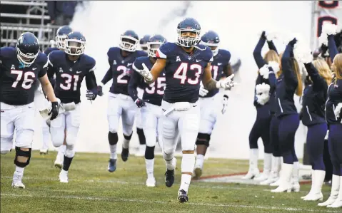  ?? Stephen Dunn / Associated Press ?? UConn players take the field before a game against Temple at Rentschler Field.