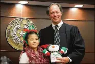  ??  ?? Judge Duggan holds a stuffed animal that was presented to him by one of the students. Duggan’s courtroom was the second one the youthful singers visited Dec. 14.